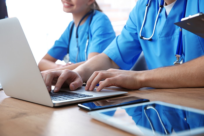 two medical professionals on laptops