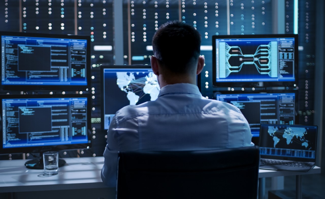 Man looking at multiple screens in security control center