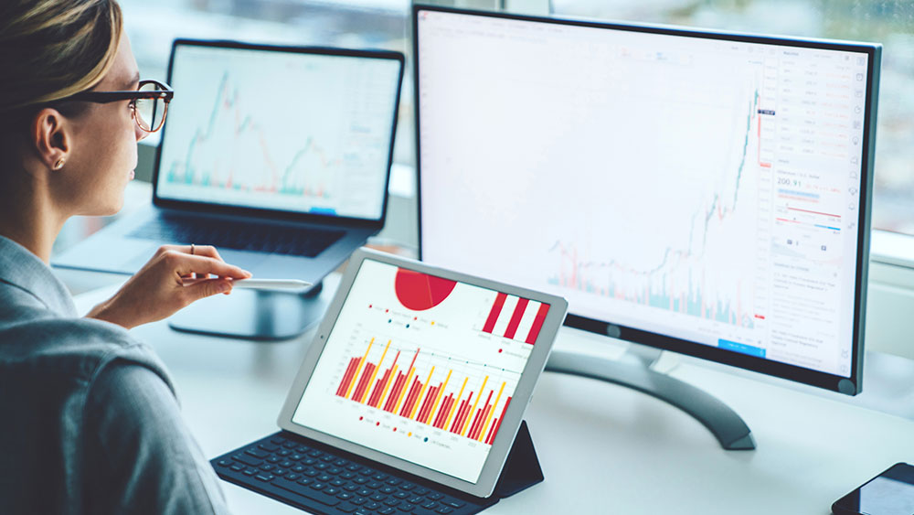 Business person viewing banking trade data on multiple screens