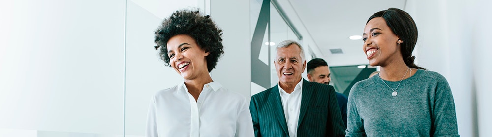 Group of professionals, two females and one male walking along office corridor