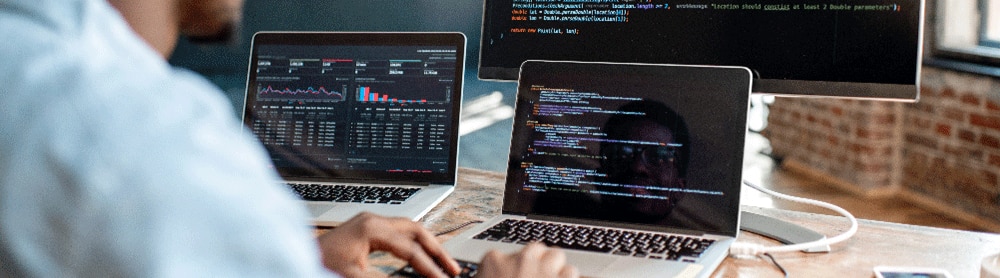 Man testing code using 3 monitors
