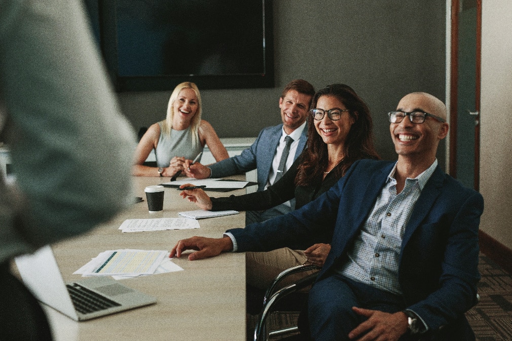 Professionals sitting around desk and smiling