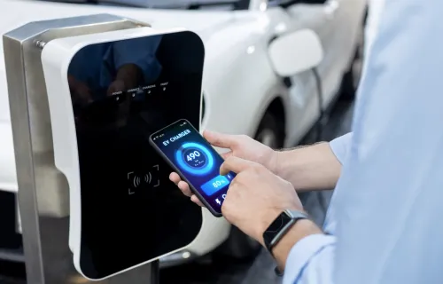 person holding mobile device to EV charging station