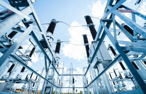 High-voltage electrical substation with steel framework and insulators under a blue sky