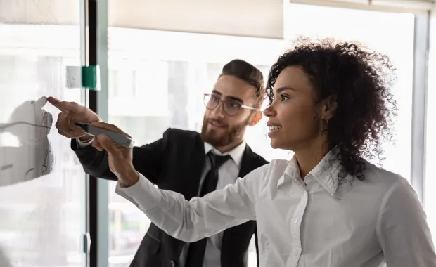two consultants pointing to strategic planning points on white board