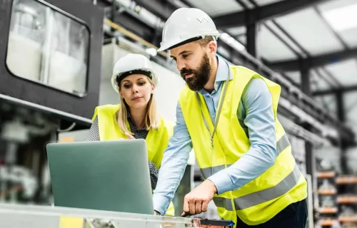 factory-workers-in-manufacturing-plant-looking-at-laptop