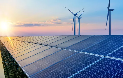 view of solar panels and wind turbines at sunset
