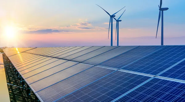 view of solar panels and wind turbines at sunset