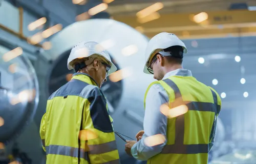 Zwei Techniker überprüfen Produktionsdaten auf einem Tablet in einer digitalen…