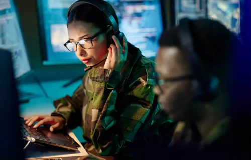 Two military personnel working in front of computer screens