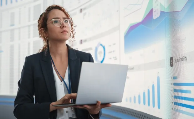 woman holding laptop analyzing data on digital screen with graphs and charts